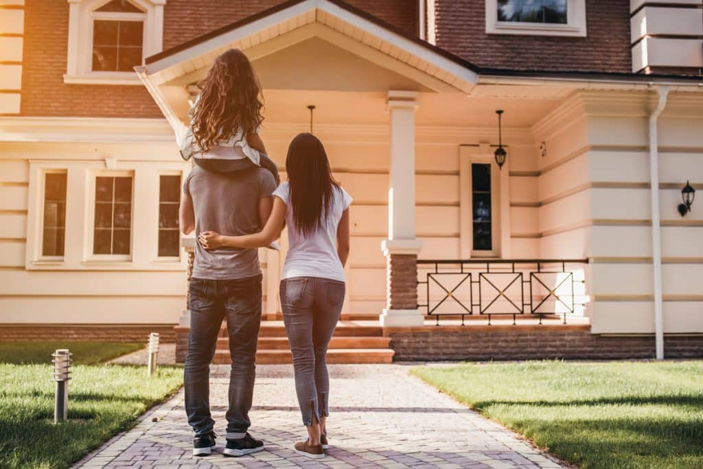 Couple with Child on shoulders looking at a home to purchase