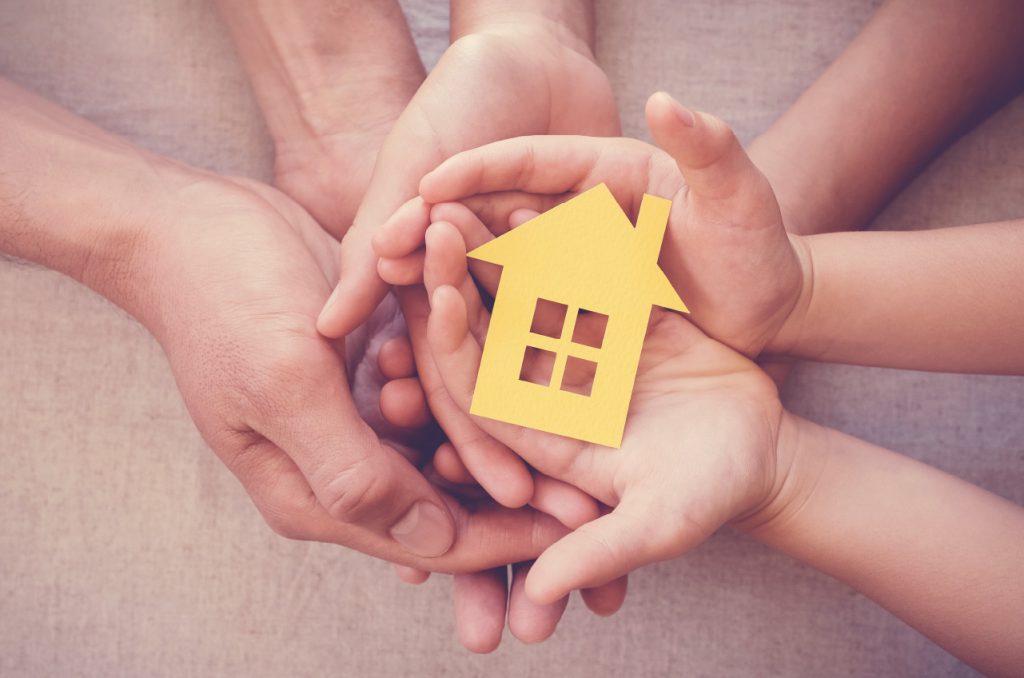 Familes hands holding an Orange paper home