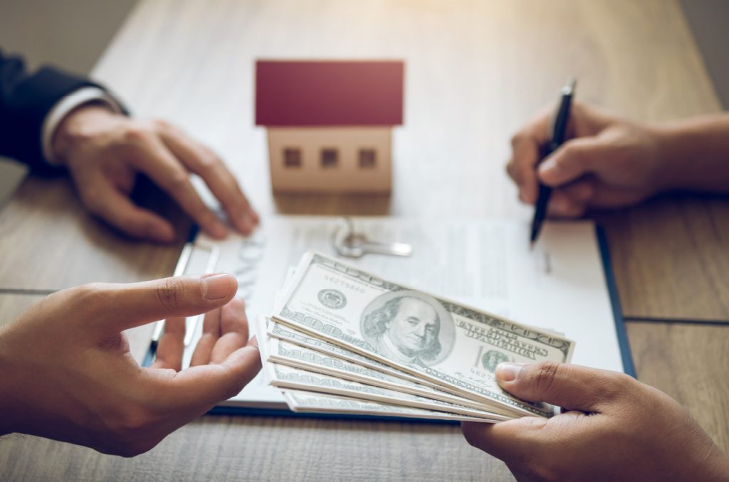 Money on a table with a toy home