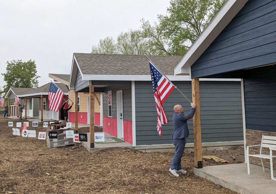 A man hanging up an American flag on his home