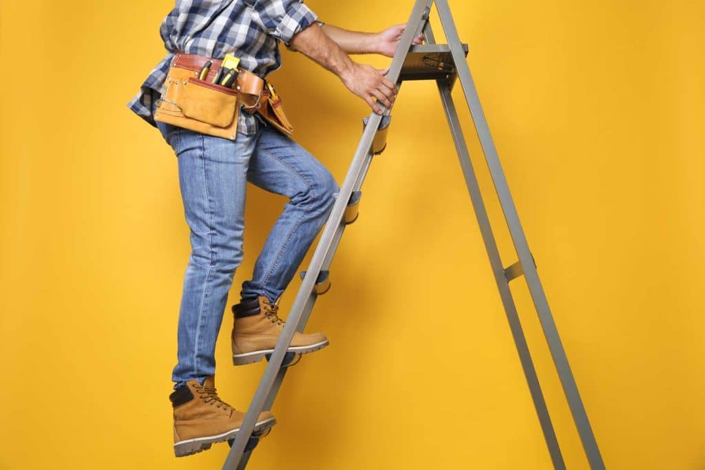 Man on a ladder with a yellow wall behind him