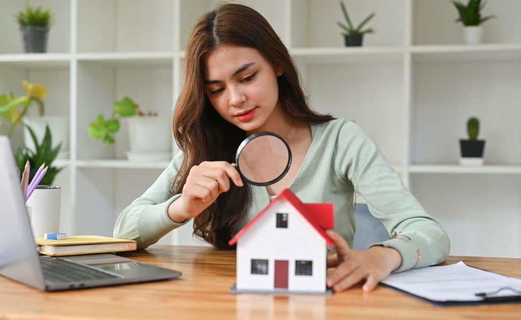A girl looking at a model home through a magnifying glass
