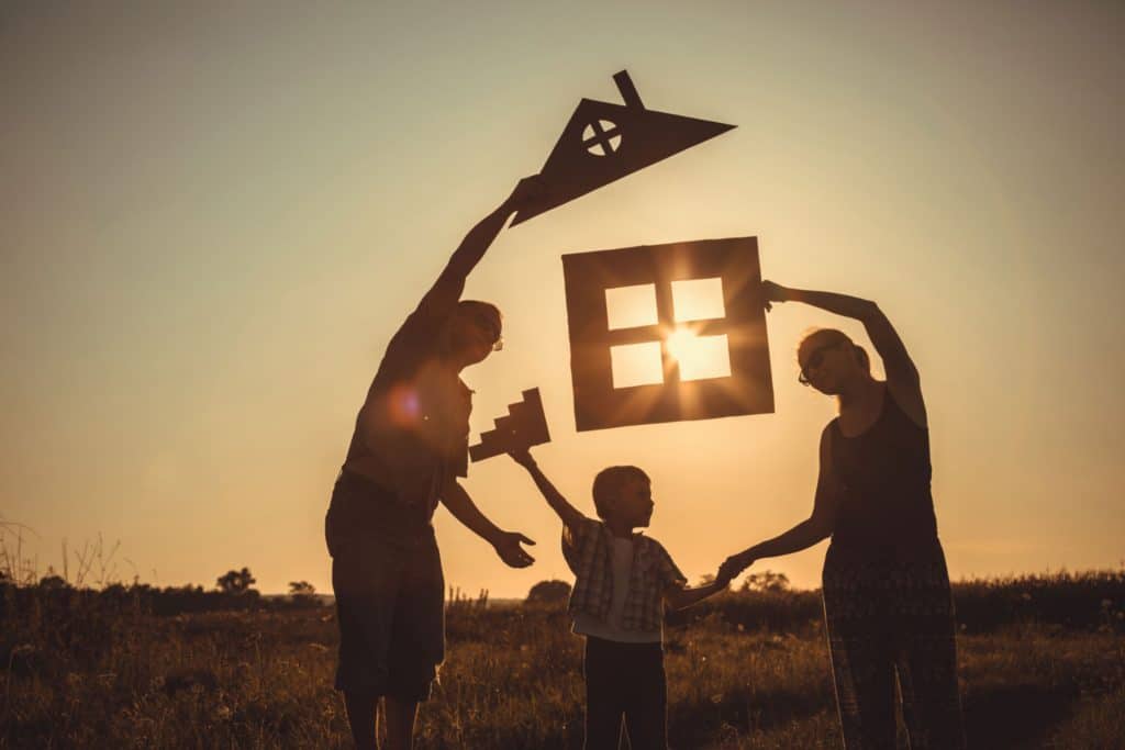 Family at sunset holding a home silohette
