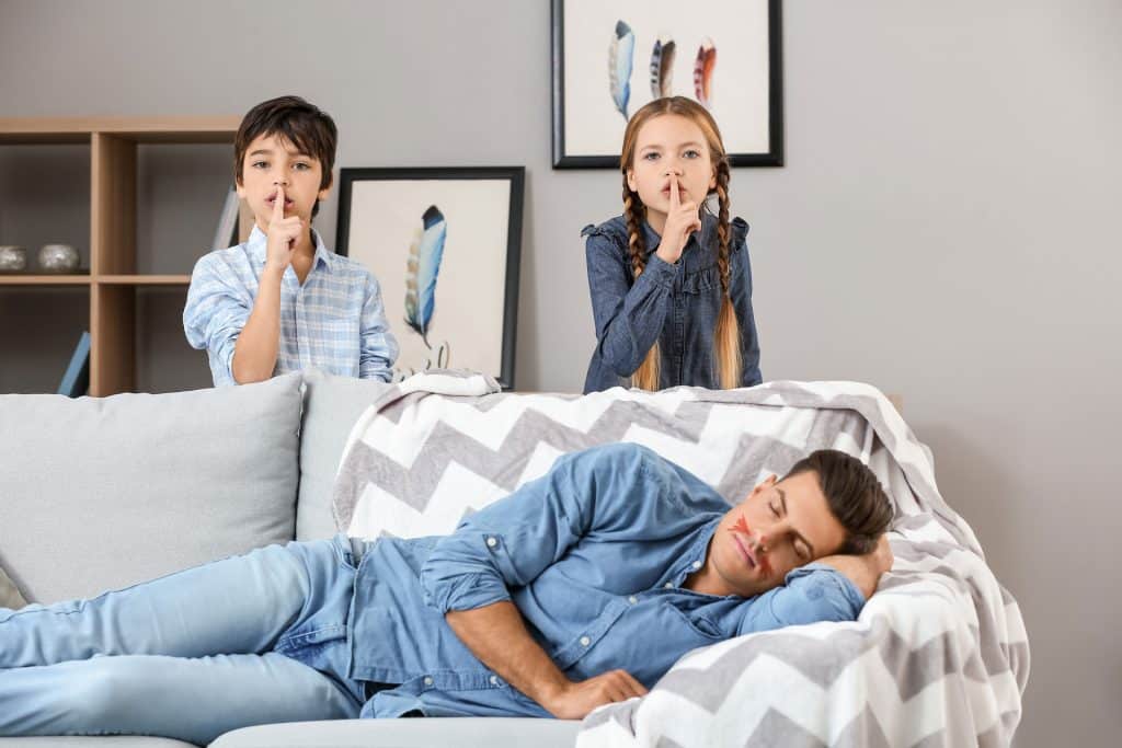 Two kids with a secret for their dad who is sleeping on the couch