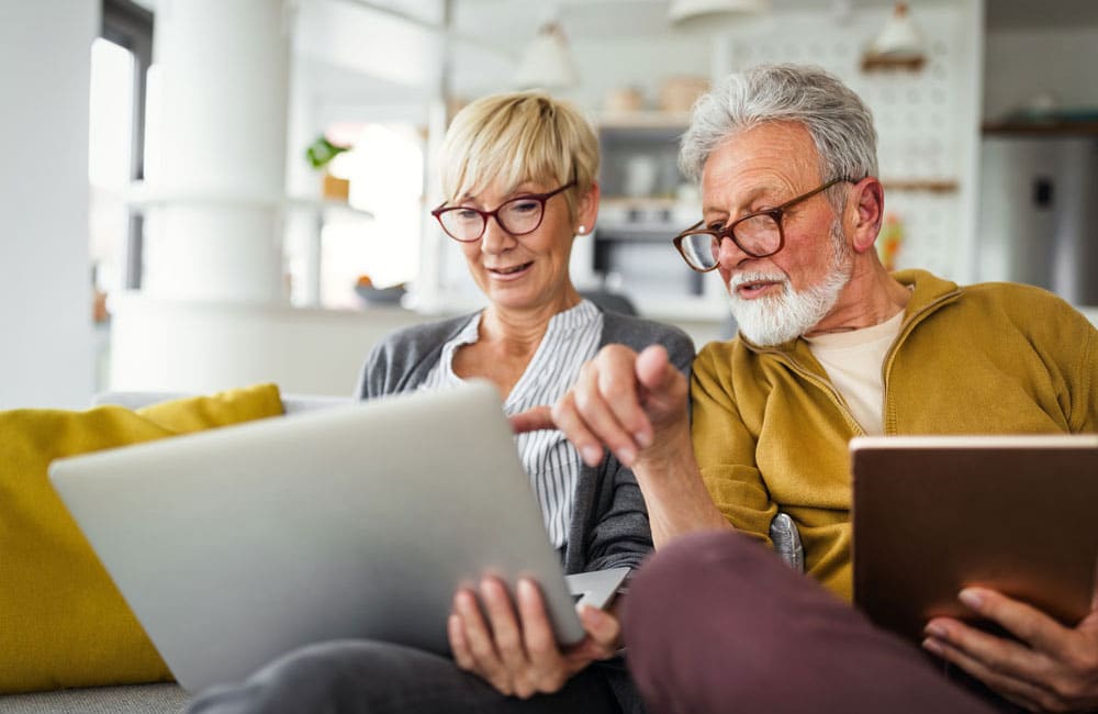 A couple inside their home looking at their laptop